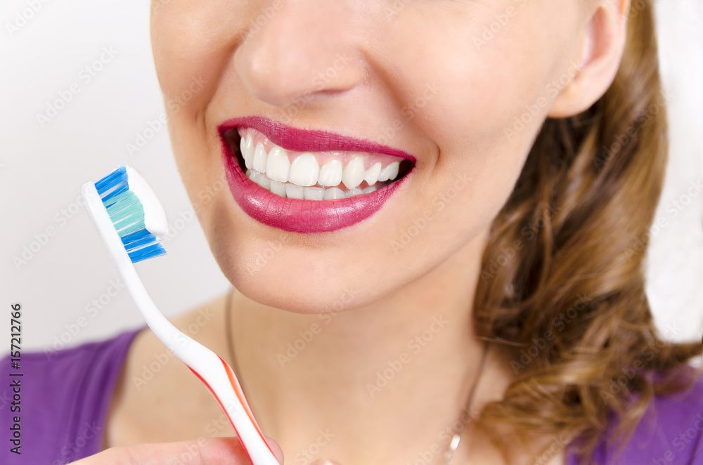 Closeup on mouth of perfect teeth woman smiling and holding toothbrush Closeup on mouth of perfect teeth woman smiling and holding toothbrush