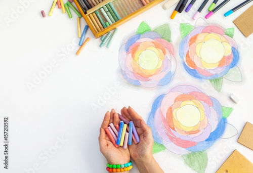 Flowers drawn art with pastels. Pencil, markers and hands of the artist on a white background. photo