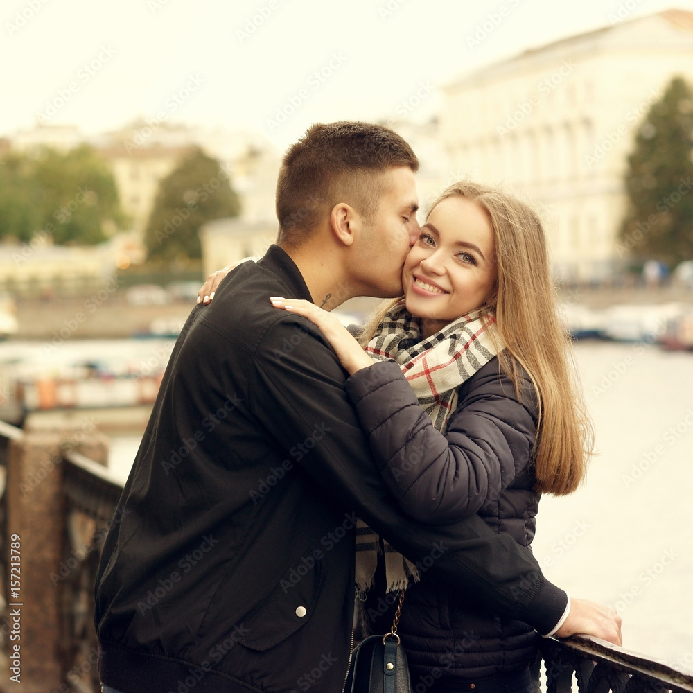 Fototapeta premium Happy joyful beautiful young romatic couple hugging and cuddling at city street on autumn or spring day