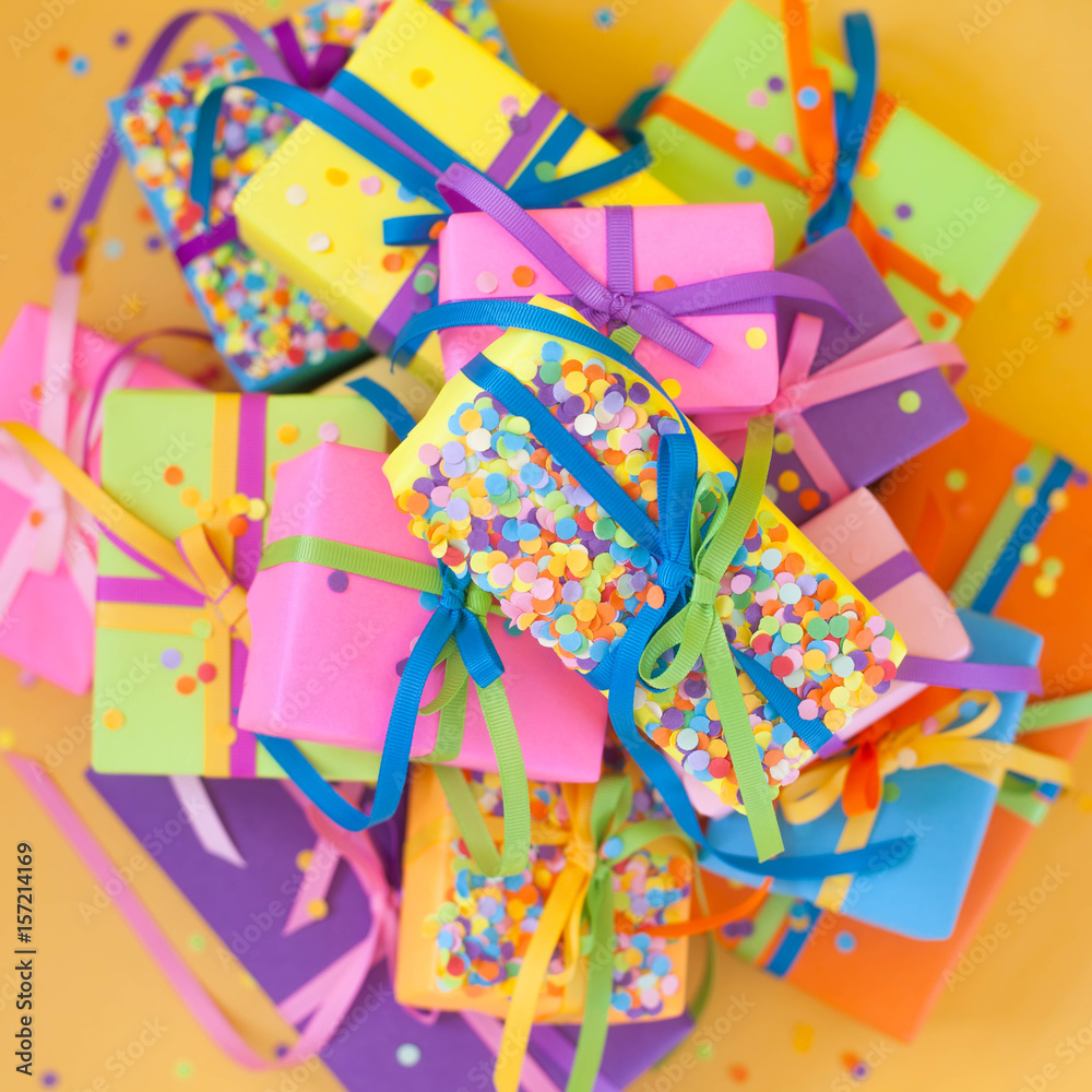 Colored gift boxes with colorful ribbons. Yellow background. Gifts for Christmas or a birthday.