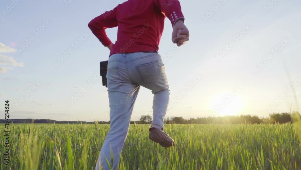 Low angle view of a successful happy businessman waving his arms with leather briefcase running in slow motion on the wheat field Low angle view of a successful happy businessman waving his arms with leather briefcase running in slow motion on the wheat field