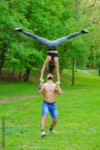 A guy and a girl are doing sports, aerial gymnastics in the park
