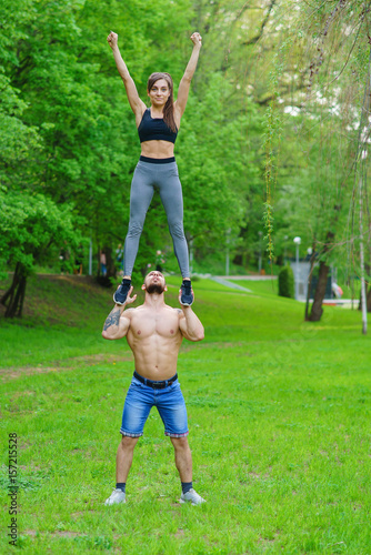 A guy and a girl are doing sports, aerial gymnastics in the park photo