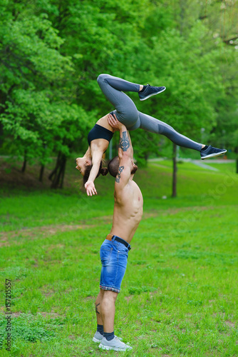 A guy and a girl are doing sports, aerial gymnastics in the park photo