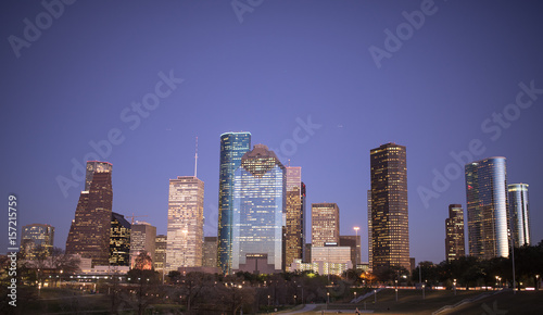the moon resting on a skyscraper in the early dusk light, buildingd overlapping eachother looking at the sun setting