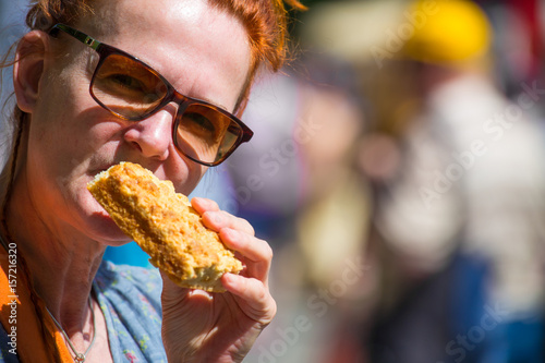 eine Frau mittleren Alters isst auf einem Strassenfest ein St  ck Kuchen
