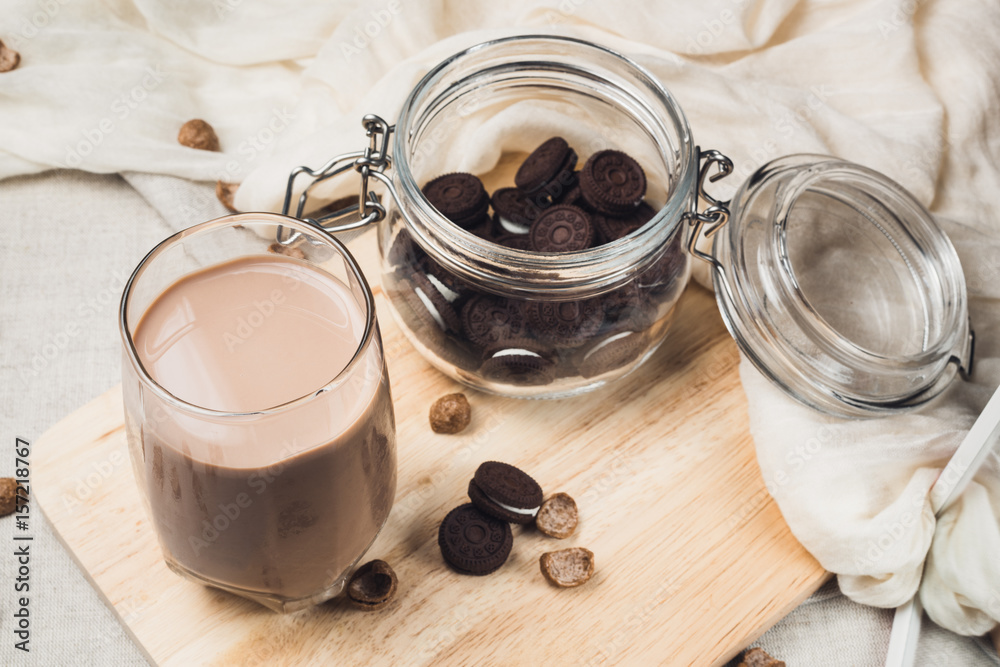 Chocolate milk with jar of cookies. Cup of cocoa on wooden board. Rustic table with grey tablecloth and white napkin Chocolate milk with jar of cookies. Cup of cocoa on wooden board. Rustic table with grey tablecloth and white napkin