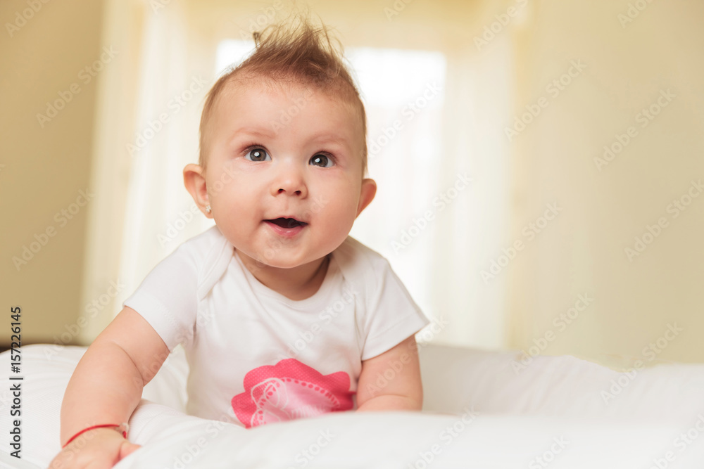smiling baby girl sitting in her bed