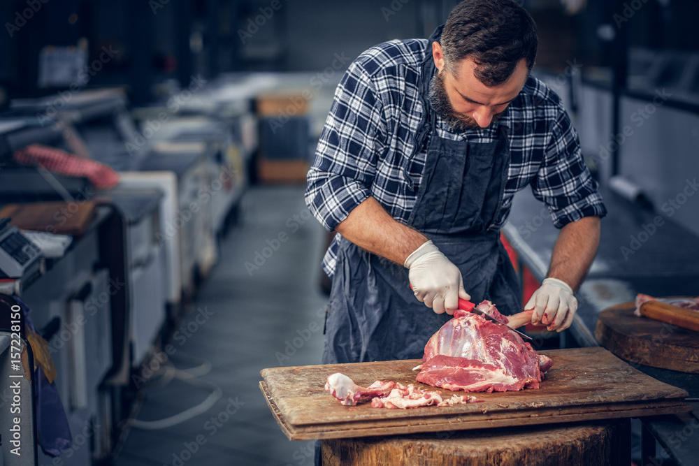 Bearded butcher cut fresh bacon meat.