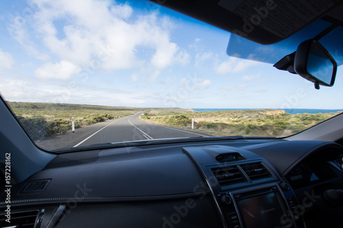 Inside of car with dashboard driving down coastal road © Simon