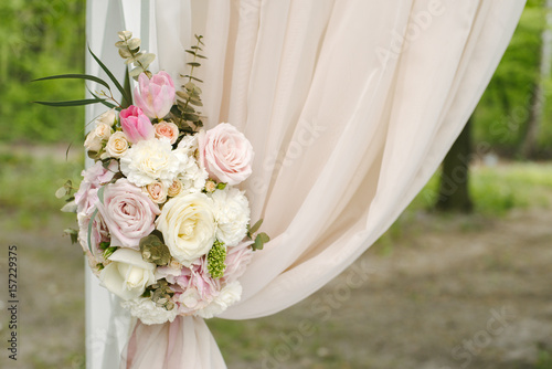 Beautiful wedding arch decorated with beige cloth and flowers