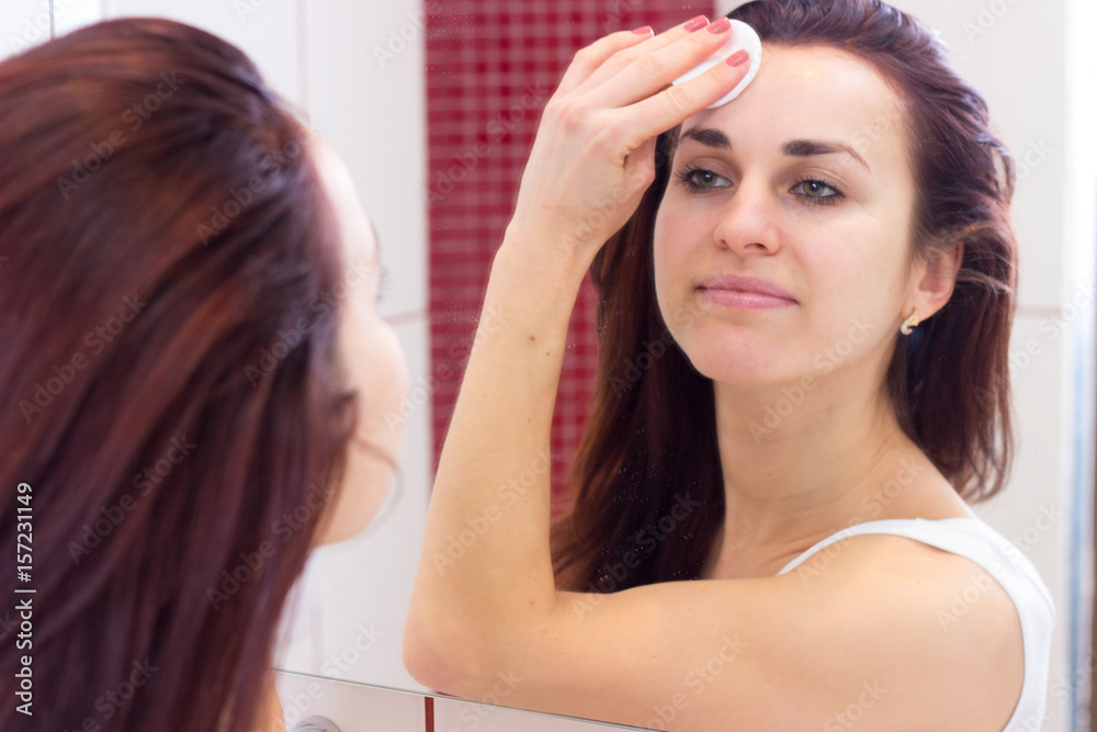 Naklejka premium Young woman removing makeup in bathroom