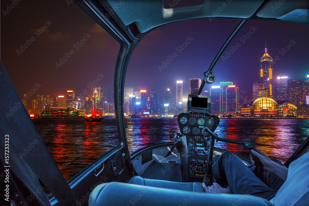 Obraz premium Helicopter cockpit flying on Hong Kong panorama skyline with pilot arm.