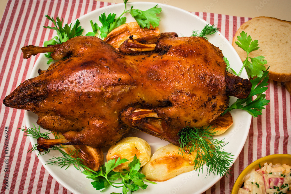 Festive baked duck with apples close-up on a plate on a table. Festive baked duck with apples close-up on a plate on a table.