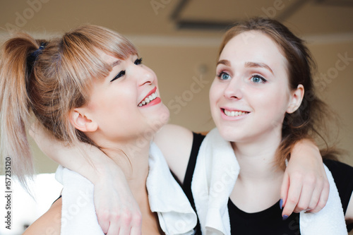  two sportive pretty women having rest after successful jogging workout in the gym. Cute female take a rest after hard physical activity Sporty friends portrait