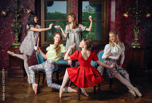 Young caucasian fashion cheerful ballerinas in a pose drinking tea