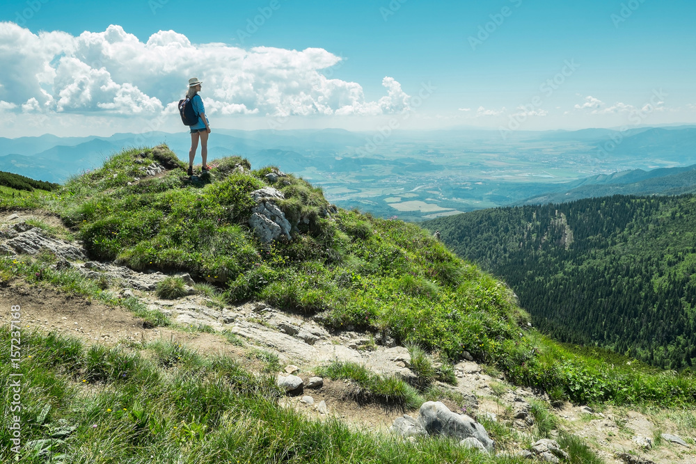 Woman hiking in mountains at sunny day time.