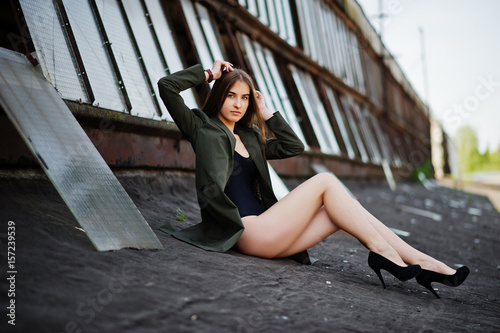 Quadro em tela Sexy model girl wit long legs at black lingerie outfit body swimsuit combidress and jacket posed at the roof of abadoned industrial place with windows