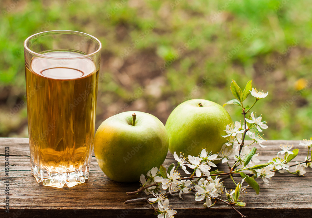 Fresh apple juice and green apples on a wooden table in the garden. Fresh apple juice and green apples on a wooden table in the garden.