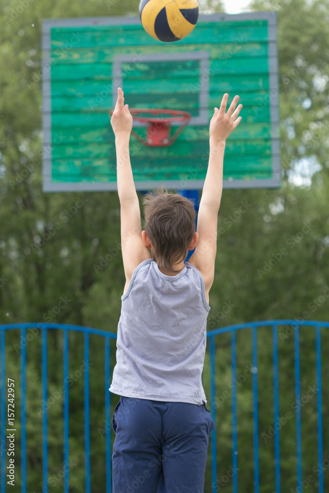Obraz premium Teen in a T-shirt and shorts throws the ball into the ring