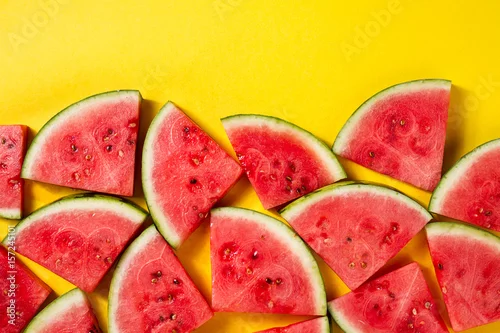 Obraz plasterki świeżego arbuza na żółtym, jasnym tle