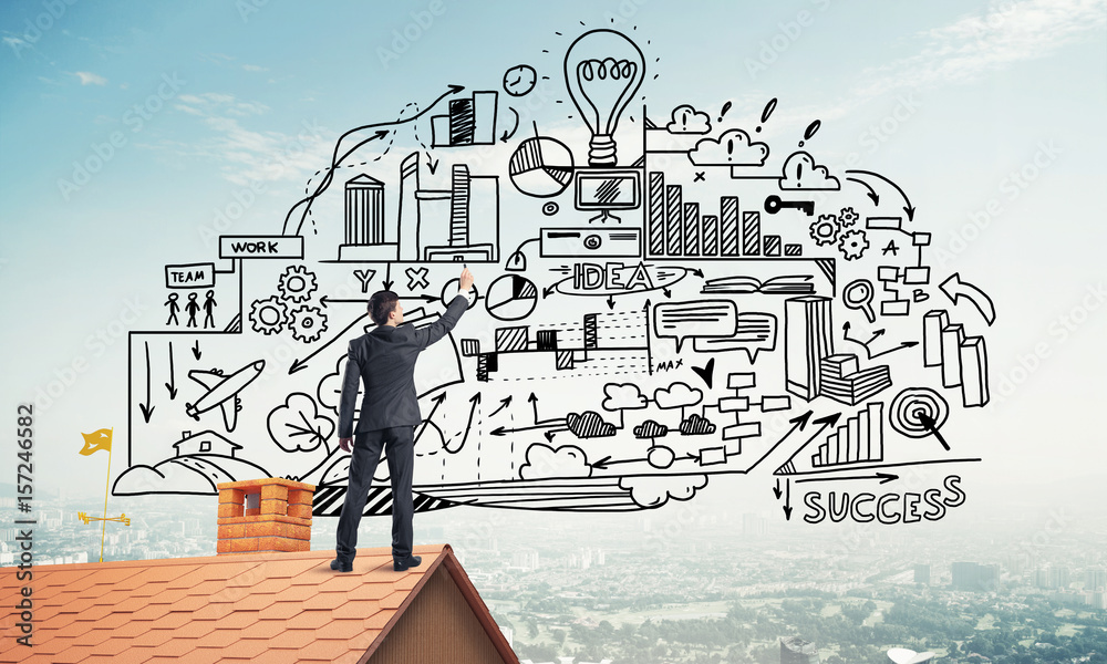 Rear view of businessman on house roof drawing his new business Rear view of businessman on house roof drawing his new business