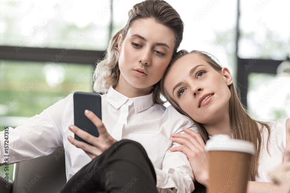 portrait of stylish woman using smartphone with girlfriend near by portrait of stylish woman using smartphone with girlfriend near by