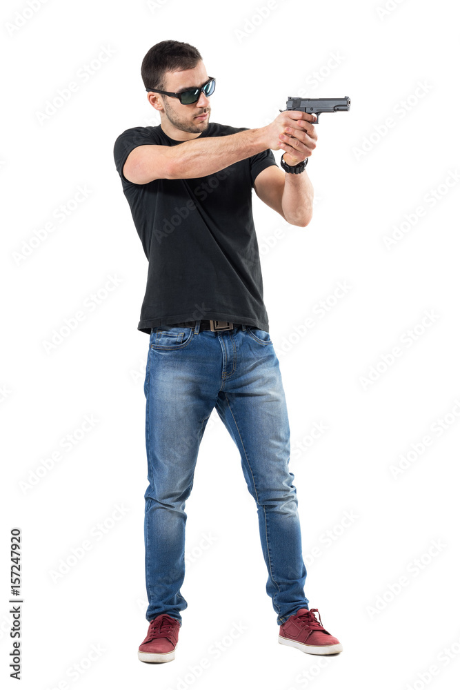 Young plain clothes policeman with sunglasses aiming gun away. Side view. Full body length portrait isolated on white studio background. Young plain clothes policeman with sunglasses aiming gun away. Side view. Full body length portrait isolated on white studio background.