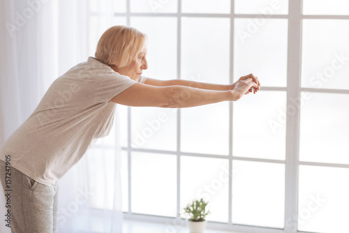 Old woman doing stretching for her back