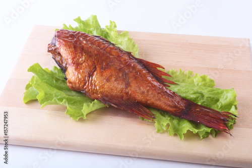 Smoked fish and lemon on green lettuce leaves on Wooden cutting board isolated on white background. photo