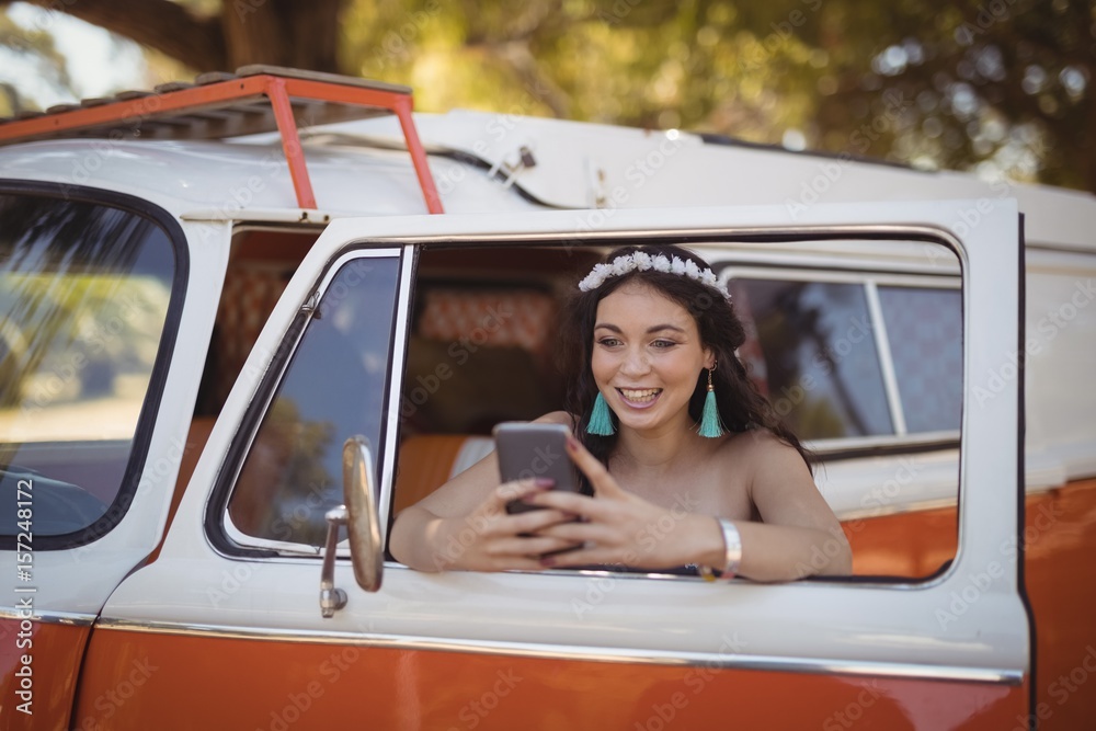 Naklejka premium Young woman using mobile phone while leaning 