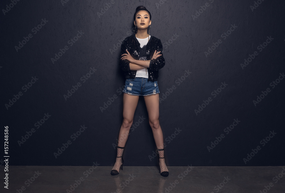 glamour attractive asian disco girl with crossed arms posing at grey wall in studio glamour attractive asian disco girl with crossed arms posing at grey wall in studio