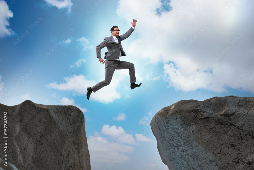 Ambitious businessman jumping over the cliff Ambitious businessman jumping over the cliff
