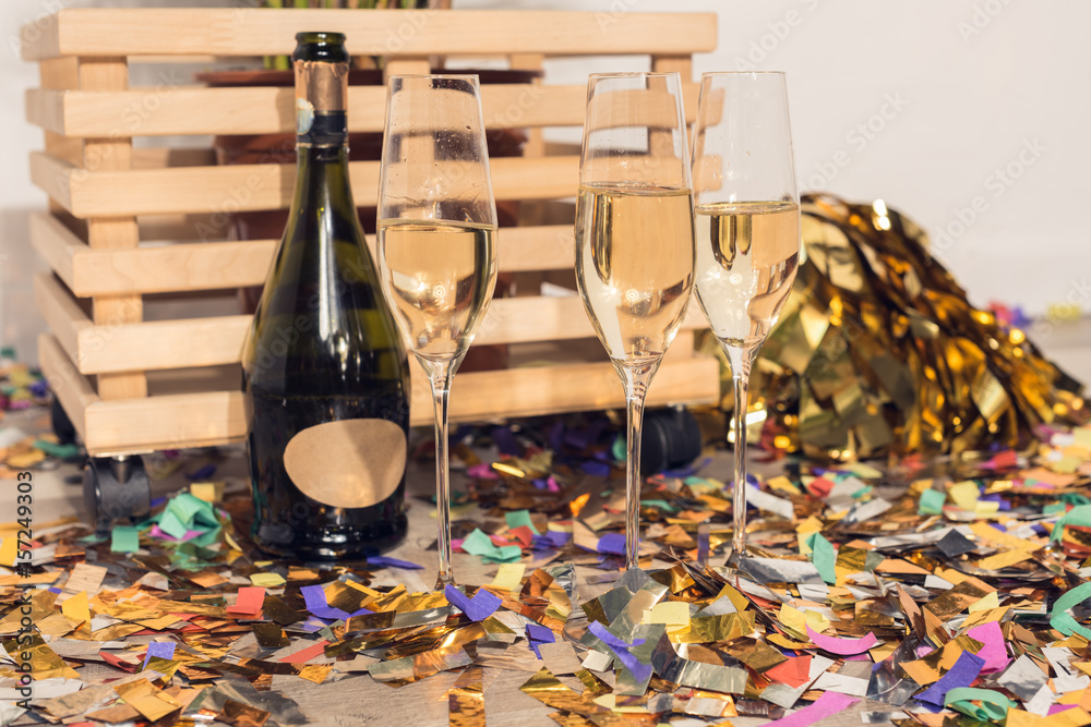 champagne in glasses and bottles with confetti and wooden box