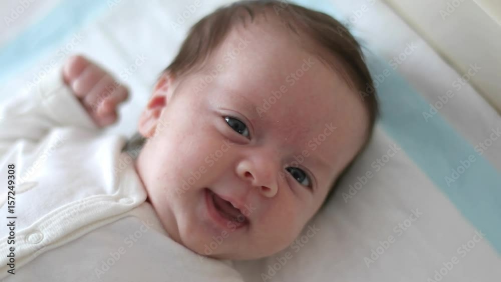 Newborn baby is looking at the camera, smiling (close-up) Newborn baby is looking at the camera, smiling (close-up)