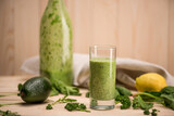Close-up view of green smoothie in glass and bottle with fresh ingredients