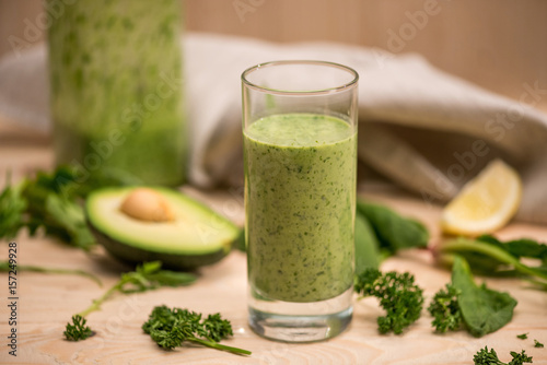 Close-up view of green smoothie in glass and fresh ingredients on table