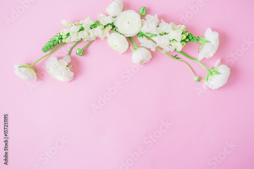 Frame made of white flowers and buds on pink background. Flat lay, top view. © artifirsov