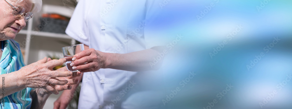 Nurse giving glass of water to senior woman Nurse giving glass of water to senior woman