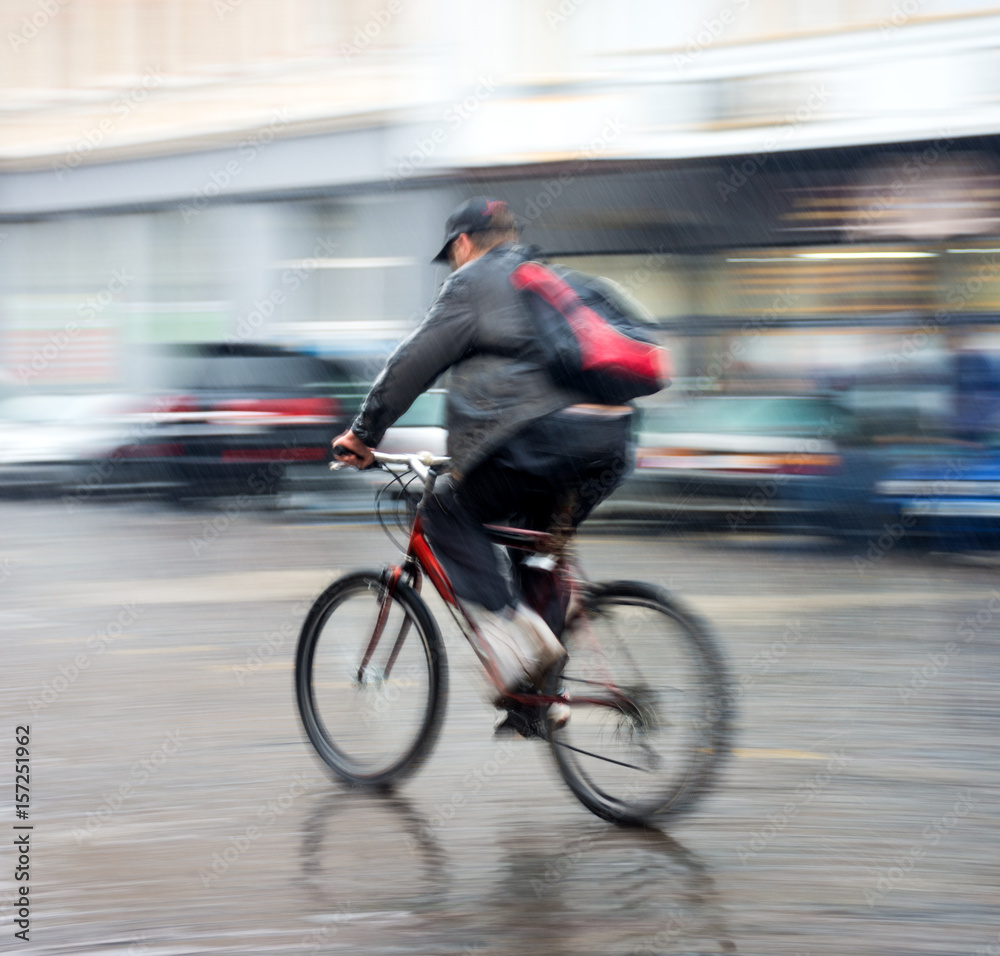 Fototapeta premium Cyclist on the city roadway in a rainy day