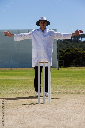 Full length of cricket umpire signalling wide ball during match