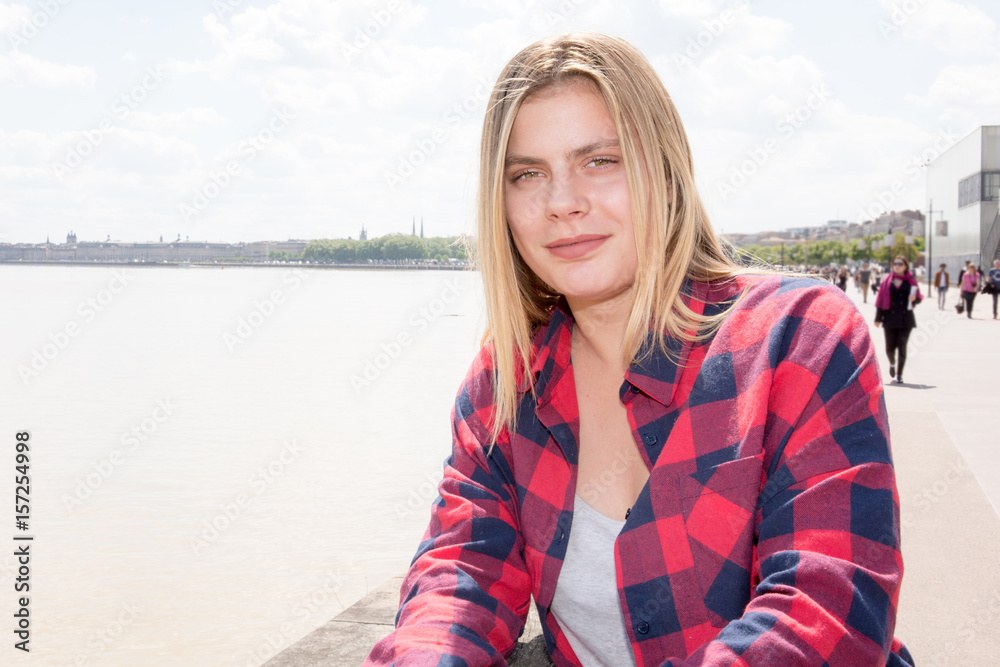 blond girl with a red and black shirt near river city