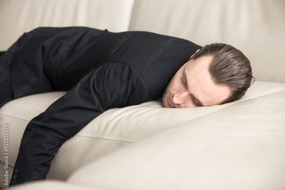 Tired businessman sleeping on sofa. Exhausted entrepreneur resting at home after hard day at work. Drunk man in knockout after night party. Deep relaxing, short sleep in office for strength recovery Tired businessman sleeping on sofa. Exhausted entrepreneur resting at home after hard day at work. Drunk man in knockout after night party. Deep relaxing, short sleep in office for strength recovery