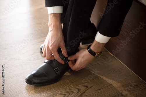 Close up image of businessman putting on  wearing stylish shoes. Guy preparing to travel  going to work in morning. Elegant accessories  comfortable footwear for business person. Business dress code