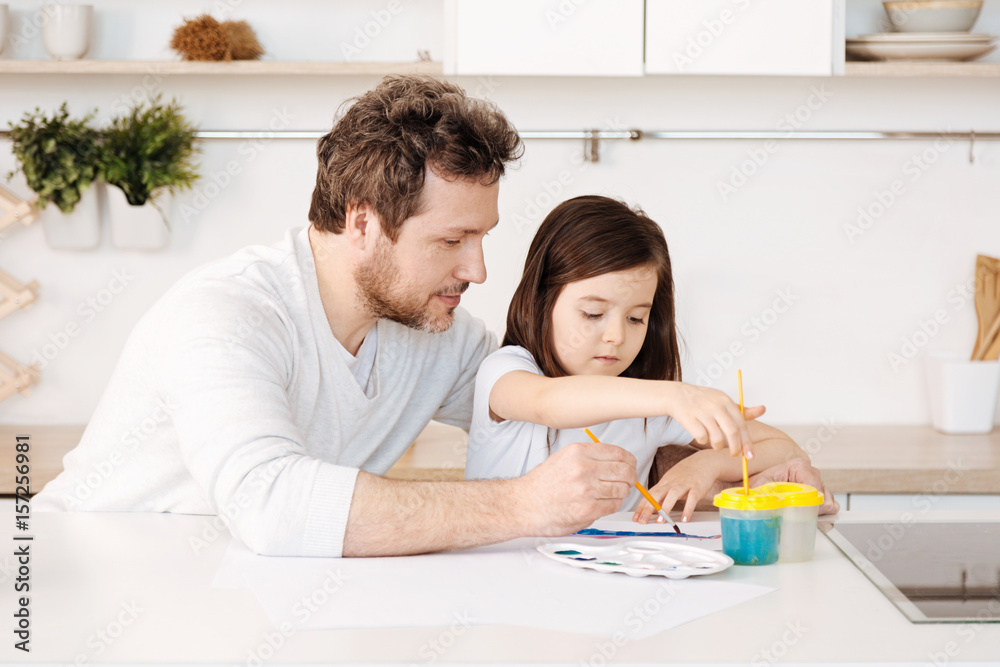 Father and his daughter engaged in the painting process Father and his daughter engaged in the painting process