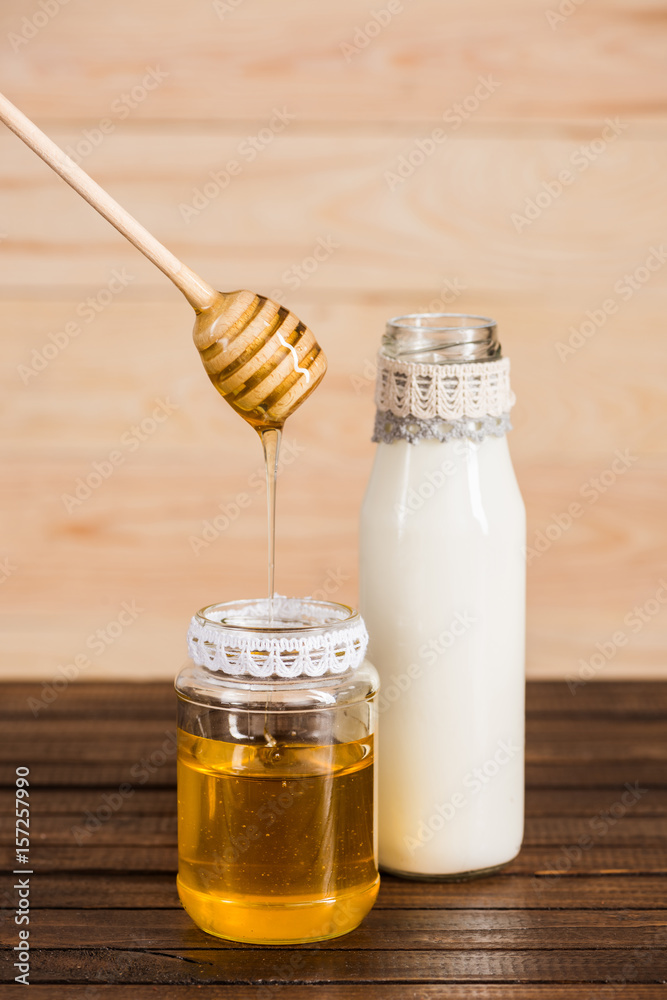 glass bottle of milk with honey in jar on wooden background glass bottle of milk with honey in jar on wooden background