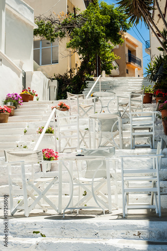 Obraz na płótnie White Greek stairs with tables and chairs. Typical Greek street with flowers w salonie