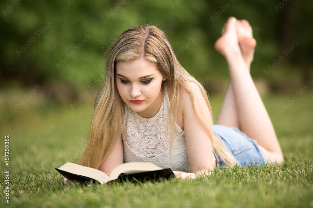 Female blonde teenager in the park with a book. Female blonde teenager in the park with a book.