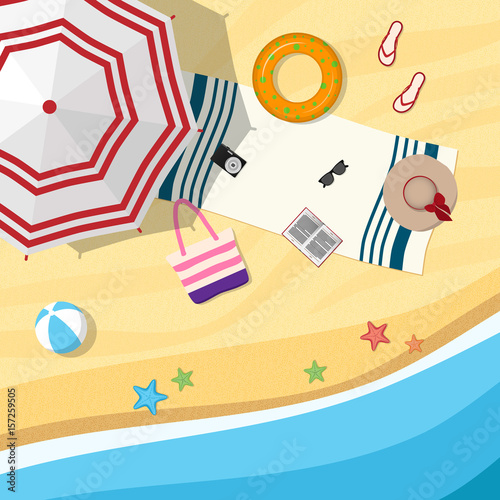 Sandy beach with an umbrella and beach accessories. Top view.