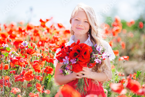 Pretty child girl with bouquet of red poppies and purple flowers